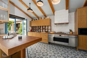 A modern kitchen with wooden cabinets, a central island, and a tiled floor.