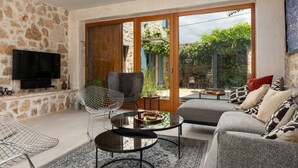 Una sala de estar con paredes de piedra, un televisor de pantalla plana, un sofá, una mesa de centro y una silla.