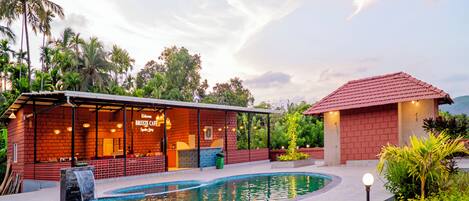 A poolside area with a bar, a small building with a red roof, and a waterfall feature.