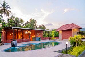 A poolside area with a bar, a small building with a red roof, and a waterfall feature. - Breeze Inn Beach Resort (Shrivardhan)