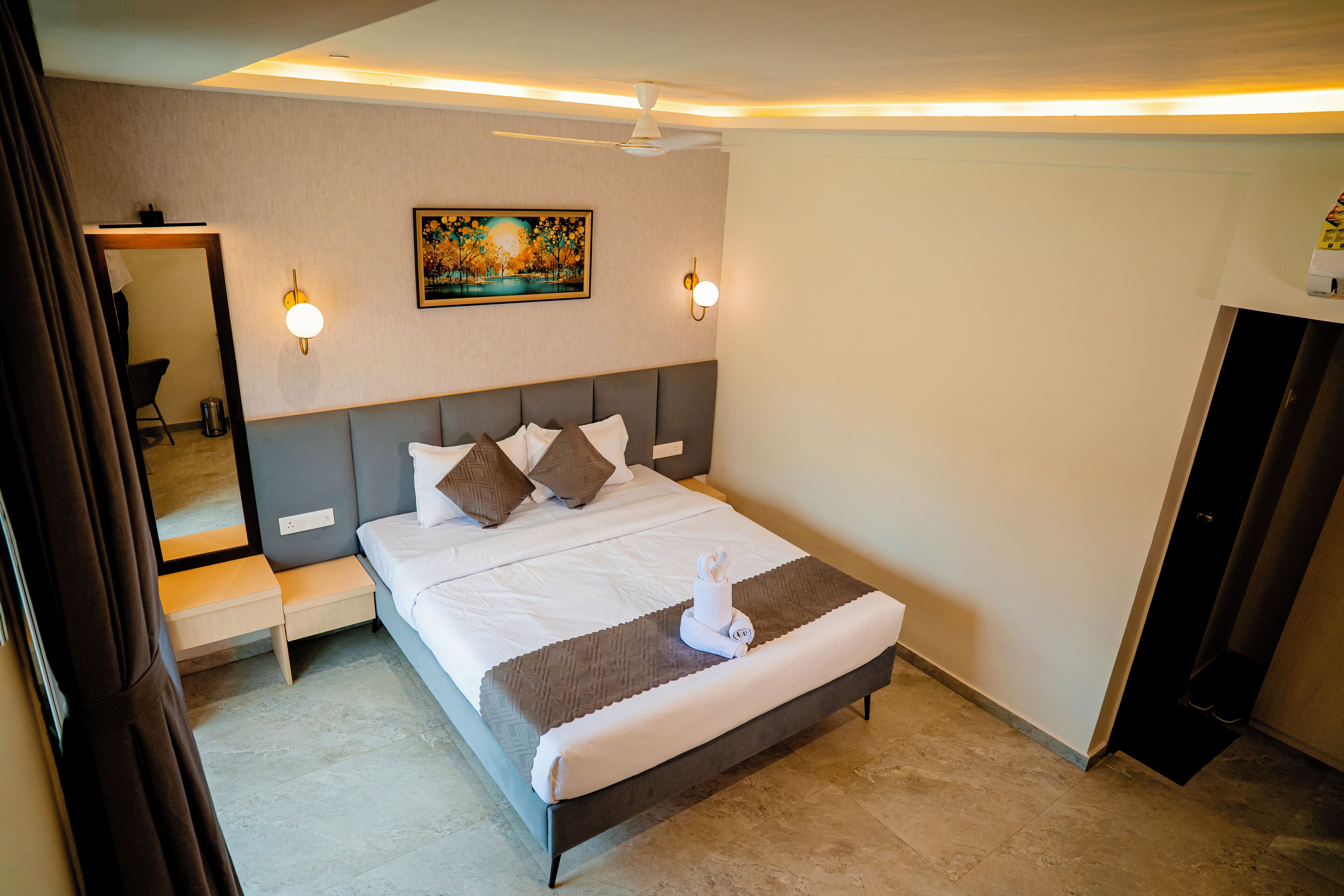 A neatly made bed with pillows, a bedside table, a wall-mounted artwork, and a ceiling fan.