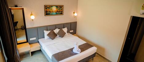A neatly made bed with pillows, a bedside table, a wall-mounted artwork, and a ceiling fan.