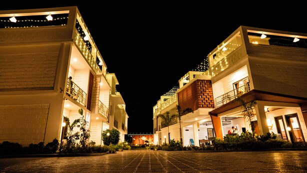 A hotel with a central courtyard, multiple floors, and balconies with string lights. - Breeze Inn Beach Resort (Shrivardhan)