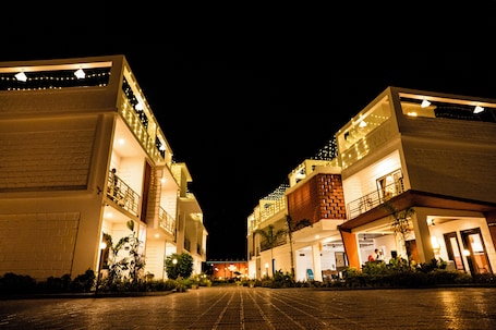 A hotel with a central courtyard, multiple floors, and balconies with string lights.