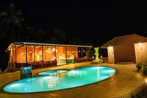 A swimming pool with a glass enclosure and a brick building with a sign that reads 'BREEZE CAFE.'