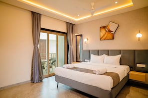 A modern hotel room with a large bed, a ceiling fan, a view to the outside, and a balcony. - Breeze Inn Beach Resort (Shrivardhan)