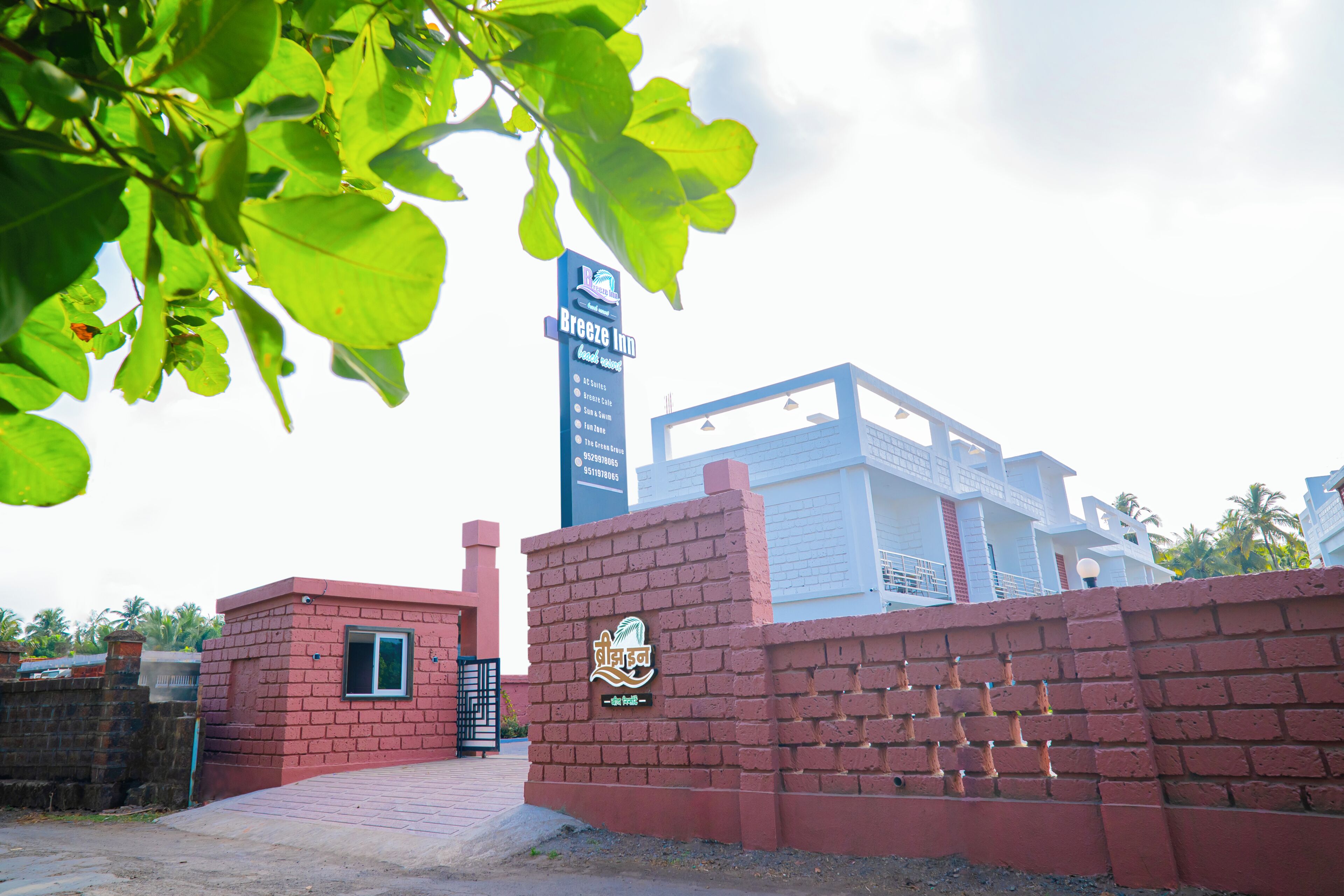 A red brick wall with a Breeze Inn sign, a gated entrance, and a modern building in the background.