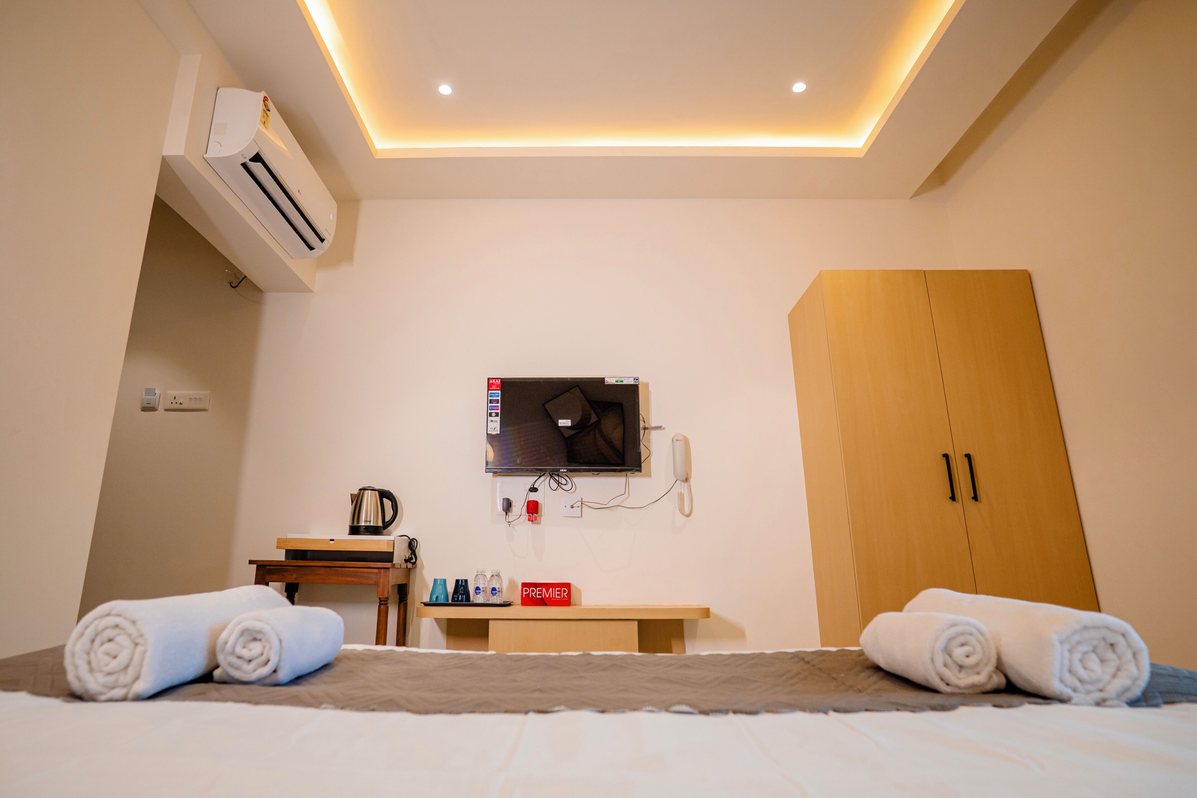Habitación de hotel con cama, escritorio con hervidor, televisión y armario.