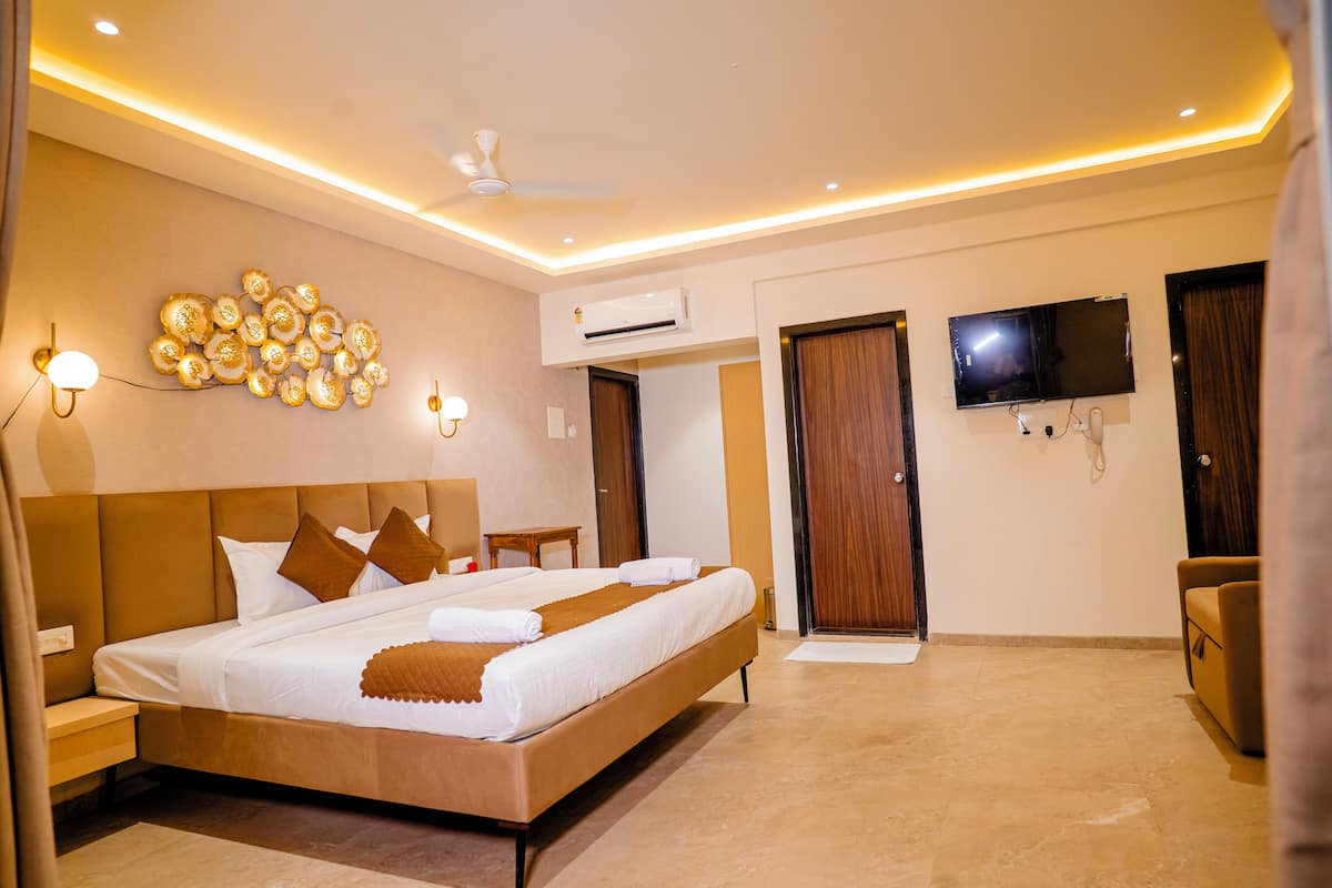 A modern hotel room with a large bed, a flat-screen TV, an air conditioning unit, and a ceiling fan.
