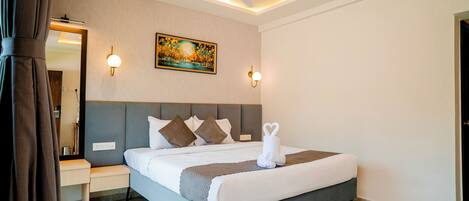 Een moderne hotelkamer met een groot bed, nachtkastje, wanddecoratie, plafondventilator en sfeerverlichting.