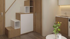 A modern interior with a wooden staircase, built-in cabinets, and a kitchen area with a sink. - Urban Nest (Hanoi)