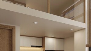 A compact kitchen with a washing machine, a refrigerator, and a dining area with a small table and chair. - Urban Nest (Hanoi)