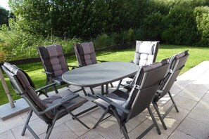 Een terras buiten met een ronde tafel en vier stoelen.