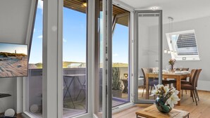 A modern interior with a dining area, a view of the beach, and a large window. - Stylish vacation apartment for up to 4 people, close to the beach with balcony and (Hörnum (Sylt))