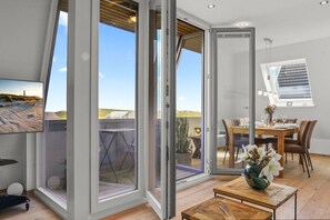 Ein modernes Interieur mit Essbereich, Blick auf den Strand und einem großen Fenster.