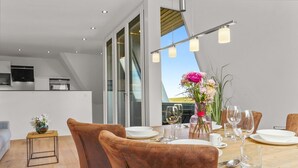 A modern dining area with a wooden table, brown leather chairs, and a vase of flowers. - Stylish vacation apartment for up to 4 people, close to the beach with balcony and (Hörnum (Sylt))