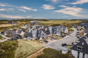Ein Wohngebiet mit modernen Häusern, einer Hauptstraße und einem Blick auf das Meer in der Ferne.