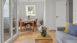 A modern living space with a dining area, a sofa, and a coffee table. - Stylish vacation apartment for up to 4 people, close to the beach with balcony and (Hörnum (Sylt))