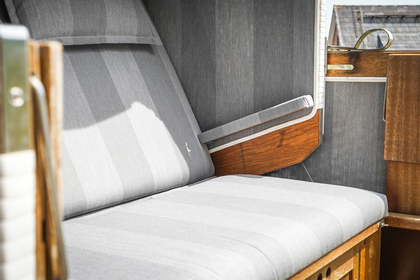 A campervan interior with a cushioned seating area, a wooden side table, and a window.