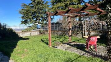 A garden area with a pergola, a red chair, and a stone pathway.