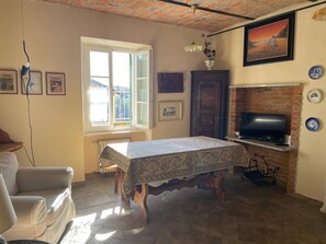 A living room with a table, a sofa, a TV, and a fireplace.