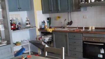 Una cocina con armarios grises, una mesa de comedor, sillas y una araña.