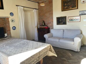 Une pièce comprenant un lit, un canapé, un mur en briques, une cheminée et un luminaire au plafond.