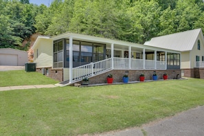 A two-story house with a covered porch, a brick foundation, and a grassy yard.