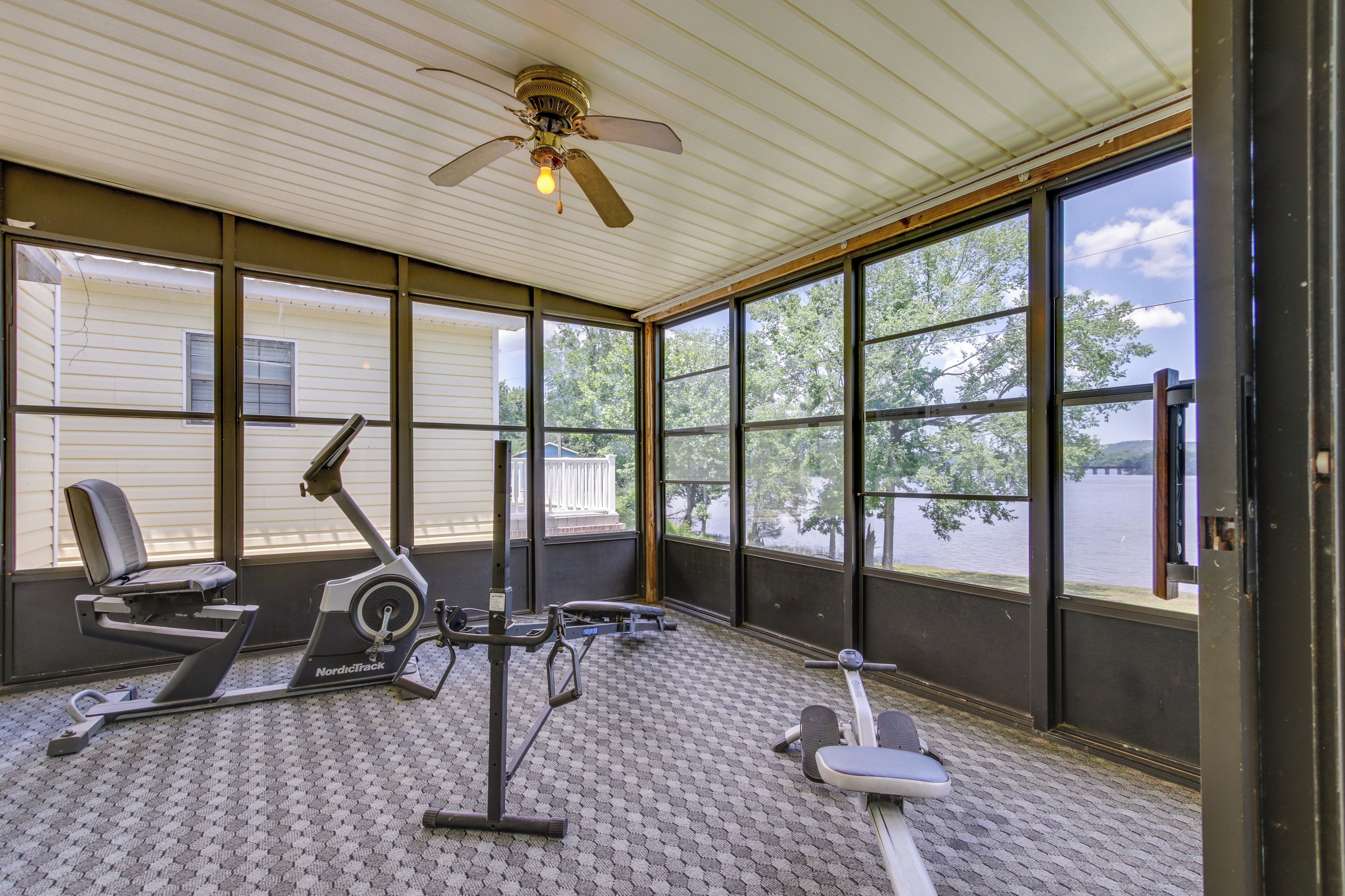 Un espace de remise en forme extérieur abrité, équipé d’appareils d’exercice, doté de grandes fenêtres et d’un ventilateur de plafond.