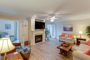 Ein Wohnzimmer mit Kamin, Fernseher, Deckenventilator und einer Couch.