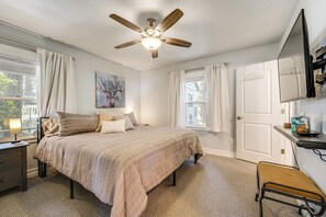 Ein Schlafzimmer mit Bett, Deckenventilator, Nachttisch, Schreibtisch und Stuhl.