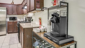 Una cocina con armarios de madera, un refrigerador de acero inoxidable, un microondas, una cafetera y un estante con frascos.