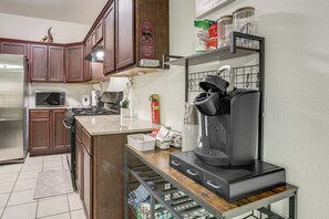 A kitchen with wooden cabinets, a stainless steel refrigerator, a microwave, a coffee maker, and a shelf with jars. - 3 Mi to Dtwn! Houston Family Haven w/ Private Yard (Houston)