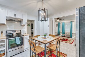 A modern kitchen with white cabinetry, a stainless steel stove, and a dining area with a table and chairs. - Peaceful Family Home Near Main St! (Franklinton)