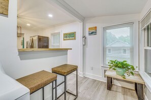 A kitchen with a countertop, two stools, a window with blinds, and a potted plant. - Peaceful Family Home Near Main St! (Franklinton)