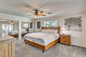 A bedroom with a wooden bed, a nightstand, a ceiling fan, and a large window. - 2 Mi to Windsor Boat Launch! Lake-View Escape (Lake Havasu City)