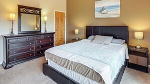 A bedroom with a bed, dresser, nightstands, and a painting of a boat on the wall. - Top of the World Townhome w/ Views in Lake George! (Lake George)