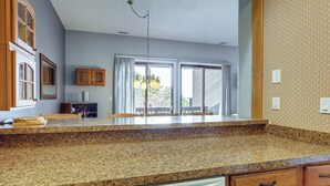 A kitchen with granite countertops, wooden cabinets, a dishwasher, and a dining area with a table and chairs. - Top of the World Townhome w/ Views in Lake George! (Lake George)