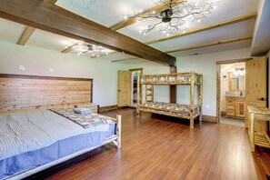 Un dormitorio con una cama de madera, una cama nido y un techo de madera con vigas a la vista.