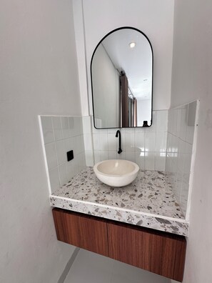 A bathroom with a white sink, a mirror, and a terrazzo countertop. - Sedana Villa (Badung)