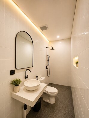Ein modernes Badezimmer mit einem weißen Waschbecken, einem Spiegel, einer Toilette und einer Dusche.