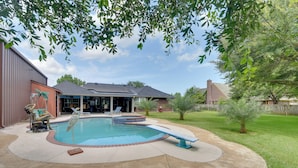 Un jardin avec une piscine, un patio couvert et une cour clôturée.