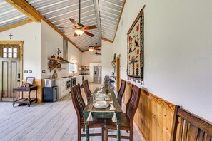 Un coin repas avec une table en bois, des chaises et un ventilateur de plafond.