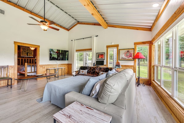 Une pièce confortable avec un grand lit, un canapé, une table en bois et un ventilateur de plafond.