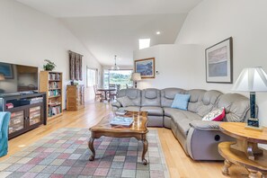 A living room with a sectional sofa, a coffee table, a bookshelf, and a television. - < 1 Mi to Beach! Ocean-View Getaway in Freeland (Freeland)