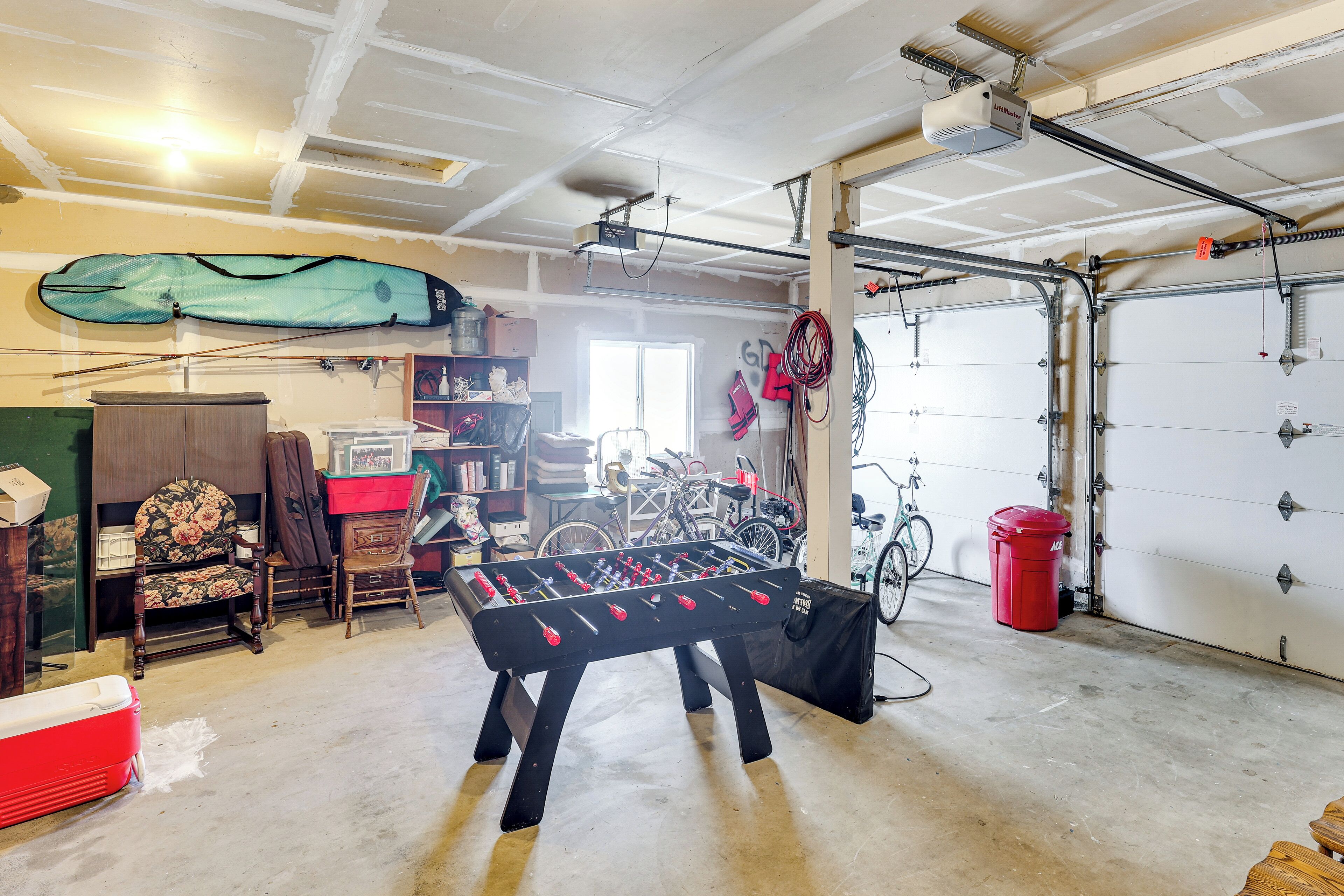 A garage with a foosball table, bicycles, and various items on shelves.