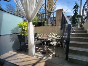 A patio with a table and chairs, a staircase, and a railing. - Stunning One Bedroom Lonsdale Quay Eco-Suite (North Vancouver)