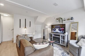 A modern living room with a sofa, armchair, TV, and fireplace. - Stunning One Bedroom Lonsdale Quay Eco-Suite (North Vancouver)
