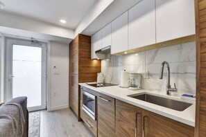 A modern kitchen with two sinks, a coffee maker, and a microwave. - Stunning One Bedroom Lonsdale Quay Eco-Suite (North Vancouver)
