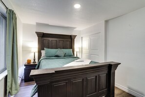 Une chambre à coucher avec un cadre de lit en bois foncé, une couvre-lit verte et une table de chevet avec une lampe.